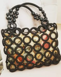 a handbag is sitting on top of a white chair with black beads and buttons