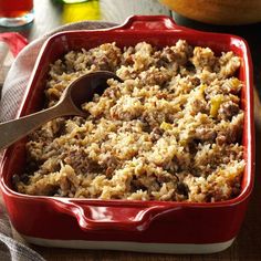 a red casserole dish filled with rice and meat