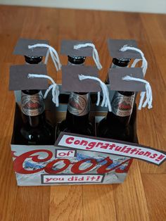 four beer bottles with graduation caps on them and a sign that says, congratulations coors