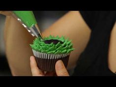 a woman is cutting into a cupcake with green icing on the top and bottom