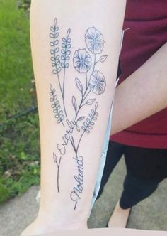 a woman's arm with flowers on it and the word love written in cursive writing