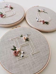 three embroidered monograms with flowers on them