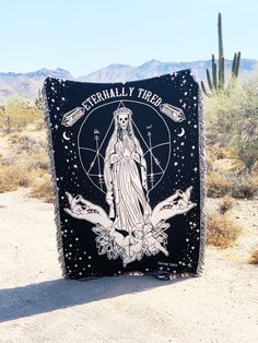 a blanket with an image of the virgin mary on it in front of a cactus