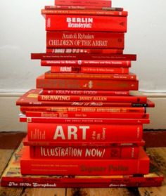 a stack of red books sitting on top of a wooden floor