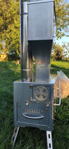 a large metal stove sitting on top of a lush green field