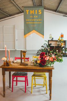 a wooden table topped with lots of flowers next to a sign that says this is an adventure