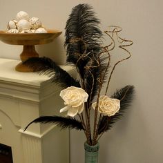 there is a vase with flowers and feathers on the table next to a cake stand