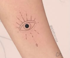 an eye tattoo on the arm with dots and lines coming out of its irise