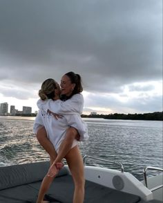 two women are hugging on the back of a boat