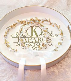 a white plate with a monogrammed k on it and a ribbon tied around the edge