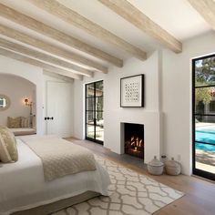 a bedroom with a fireplace and large glass doors leading to an outdoor swimming pool in the background