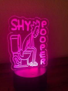 a neon sign that says, shy poopie on it's side in front of a dark background