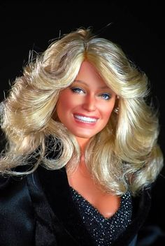 a barbie doll with blonde hair wearing a black dress and smiling at the camera, on a black background