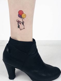 a small tattoo on the ankle of a woman's foot with a penguin holding balloons