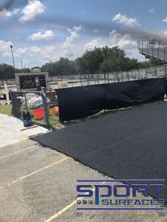 the tarp is laying on top of the black tarp in front of an empty bleachers