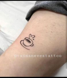 a small coffee cup tattoo on the thigh