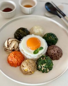 a white plate topped with different types of food next to cups and spoons on top of a table