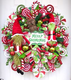 a christmas wreath with candy canes and elf hats hanging on the front door,