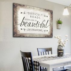 a dining room table and chairs with a sign above it that says difficult roads often lead to beautiful destinations