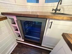 an empty refrigerator in a kitchen next to a sink and counter top with no door