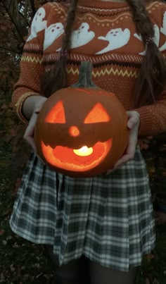 a girl holding a carved pumpkin in her hands