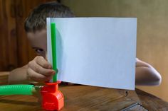 a young boy sitting at a table with a piece of paper in front of him