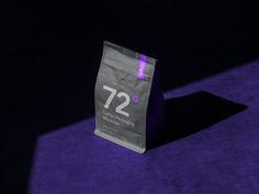 a coffee bag sitting on top of a purple carpet next to a black wall with the number 72