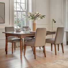 a dining room table with chairs and a vase filled with flowers on top of it