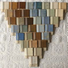 a heart shaped wall hanging made out of different colors of fabric and wood strips on a white lace doily