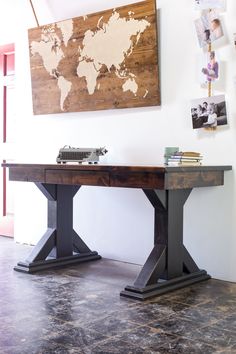 a desk with a world map on the wall above it and an old typewriter