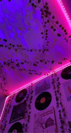 a wall covered in vinyl records and vines with purple lights on it's sides