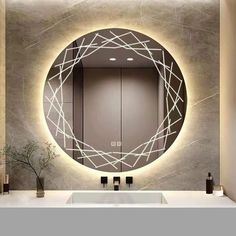 a bathroom with a round mirror and lights on the wall above it, along with a vase filled with flowers