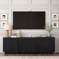 a living room with a large flat screen tv mounted on the wall above a black cabinet