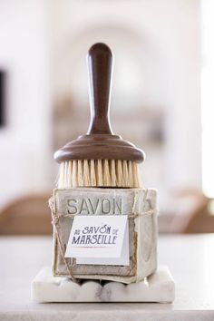 a wooden brush sitting on top of a white tile counter next to a sign that says savon