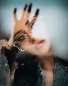 a woman wearing glasses and holding her hand up to her face