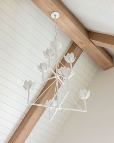 a chandelier hanging from the ceiling in a room with white walls and wood beams