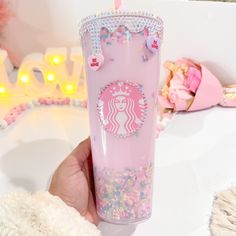 a hand holding a pink starbucks cup with sprinkles