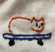 a close up of a piece of cloth with an animal drawn on it and some thread