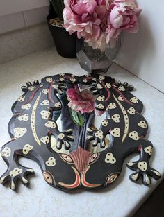 a vase filled with pink flowers sitting on top of a counter next to a flower pot