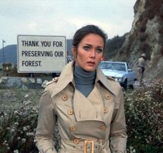 a woman standing in front of a sign that says thank you for preserving our forest