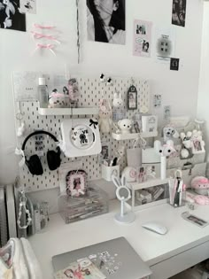 a white desk topped with lots of items next to a wall covered in pictures and photos