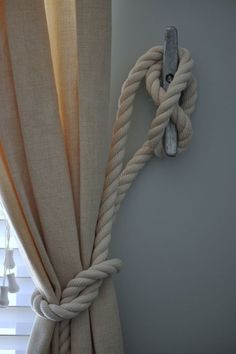 a rope hanging on the side of a window next to a light bulb and curtain