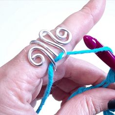 someone is knitting something with blue yarn and silver wire on their thumbnails while holding it in the palm of their hand