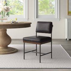 a black chair sitting in front of a table on top of a white area rug