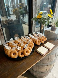 there are many doughnuts on the table next to some wine glasses and flowers