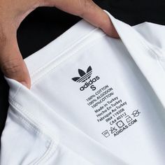 a person holding onto a white adidas t - shirt