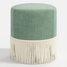 a green and white stool with tassels on the bottom, in front of a white background