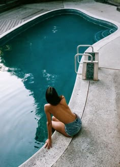 a person sitting on the edge of a swimming pool