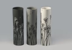 three tall vases with black and white designs on the sides, one has dandelions in it