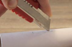 a person is holding a knife over a roll of paper and cutting it into smaller pieces